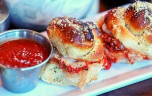 Garlic roll sliders with a side of homemade sauce available for delivery