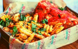 Waffle fries with basil and parmesan cheese alongside a meatball parm sub